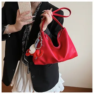 Detail of red pebbled leather hobo bag with elephant charm on casual model outfit