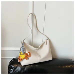 Detail of creamy white crossbody bag with lychee texture and cute elephant charm