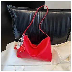 Detail of red hobo bag with lychee texture and cute elephant charm and heart chain