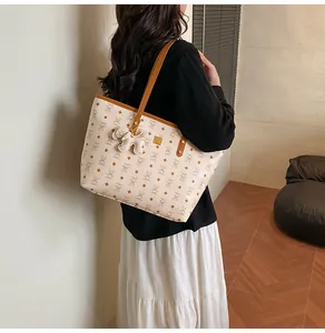 Modell trägt große cremefarbene Tote Bag mit Bärenprint und braunen Ledergriffen