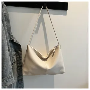 Detailed view of cream hobo bag with litchi grain texture and vertical stitch detail