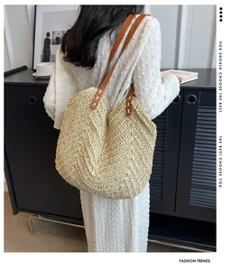 Détail du sac cabas en paille tressée avec bandoulière en cuir brun et couture en croix