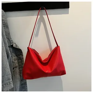 Close-up of red lychee textured leather bag with metallic zipper and shoulder strap