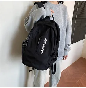 Vue détaillée du sac à dos noir en nylon avec lettrage blanc et boucle de serrage latérale