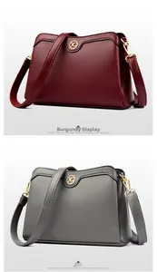Detail view of burgundy and dark grey leather bags with gold XG logo and litchi texture