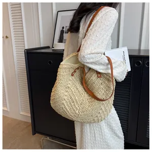 Détail du motif tressé en V et des bandoulières en cuir marron sur le sac en paille
