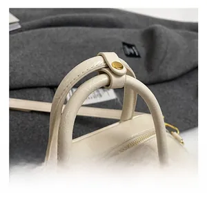 Detail of cream Boston bag with double handles and golden metal zipper hardware