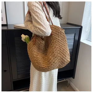 Détail d'un sac en paille tissé à la main avec bandoulière en cuir et finitions de couture