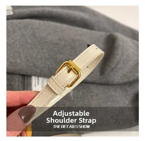 Detail of adjustable cream leather shoulder strap with gold buckle and fine stitching
