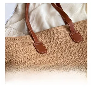 Detail showing high-quality stitching and texture of woven straw tote bag with leather strap