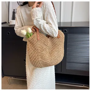Détail du tissage d'un sac cabas en paille marron avec des anses en cuir robustes