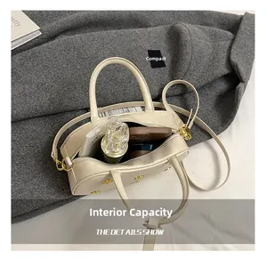 Internal capacity of beige boston bag showing space for perfume and phone
