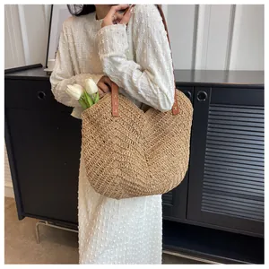 Détail du sac cabas en paille tissée avec anses en cuir marron et coutures en croix