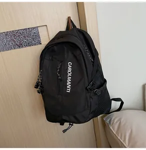 Détail d'un sac à dos en nylon noir avec texte CAROLMANTI et poche latérale sur un crochet