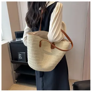 Detail view of large straw tote bag featuring brown leather handles and woven texture