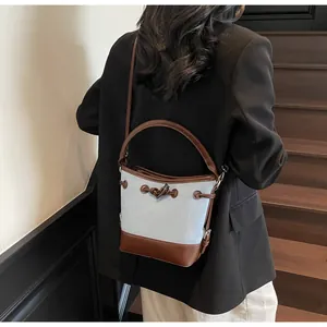 Dettaglio della borsa a secchiello in tela azzurra con cinturini in pelle marrone e coulisse