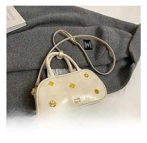 Close-up of cream Boston bag with decorative gold floral hardware and leather texture