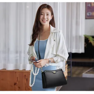 Minimalist black leather crossbody bag for women with gold logo hardware and strap
