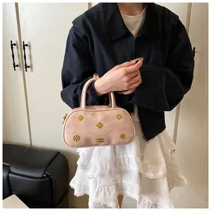 Detail of pink Boston bag featuring golden flower hardware and pebble leather texture