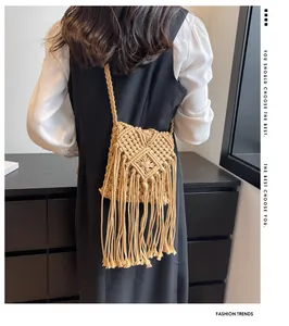 Dettaglio della borsa bohémien in paglia con lunghe nappe e tracolla intrecciata