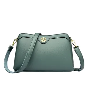 Minimalist dark green crossbody bag with pebbled leather texture and gold metal logo
