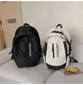 Vue détaillée de sacs à dos décontractés en nylon noir et blanc sur un canapé en cuir blanc