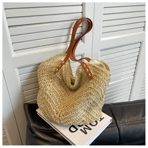 Détail du sac à bandoulière en paille tressée avec lanières en cuir brun et texture