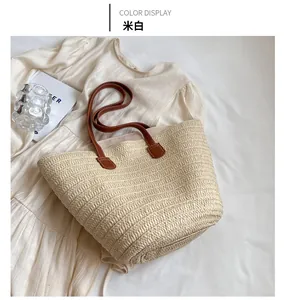 Detailed close-up of an off-white straw tote bag with brown leather handles on a summer dress