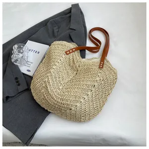Détail du sac cabas en paille tissé main avec bandoulière en cuir brun et coutures