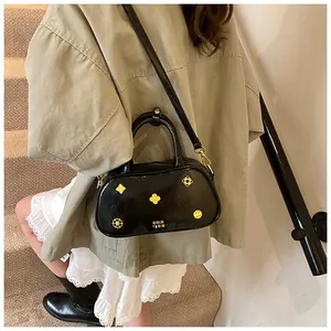 Macro detail of black glossy Boston bag with gold flower rivets and embossed text