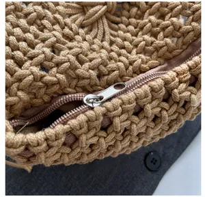 Detail showing smooth silver metal zipper and woven khaki cotton texture of straw bag