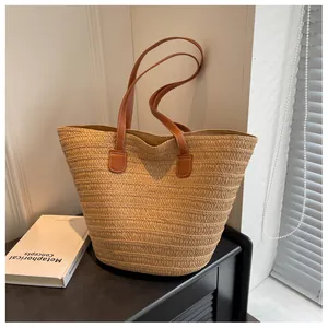Close-up of woven straw tote bag texture with brown leather handles and stitching