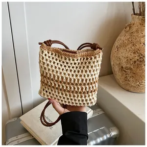 Vue détaillée du sac seau en paille tressée beige avec bandoulière en cuir nouée
