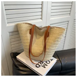 Close-up of woven straw tote bag featuring brown leather handles and fine stitching