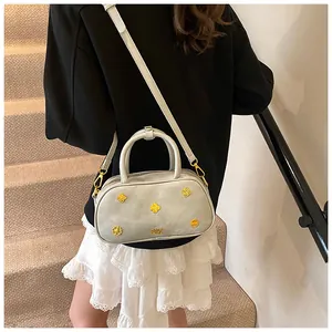 Rear view of a model wearing the grey Boston bag with golden hardware and clover details
