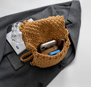 Detail showing the internal capacity of the khaki straw woven bag with a phone and wallet