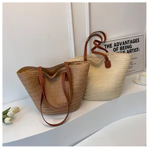 Detail of straw woven tote bags in brown and cream colors with faux leather straps