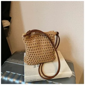 Détail du sac bandoulière en paille tressée avec bandoulière en cuir et nœuds
