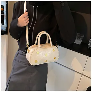 Close-up of cream Boston bag with clover stud and textured synthetic leather for women