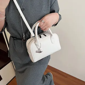 White lychee pattern Boston handbag with silver whale pendant shown on a model