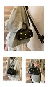 Detail view of a black Boston bag featuring gold floral metal accents and crossbody strap
