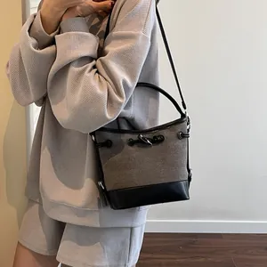 Borsa a secchiello in tela con finiture in pelle e alamaro indossata da modella