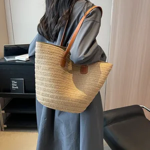 Large beige hand-woven straw tote bag with brown leather handles for beach or travel