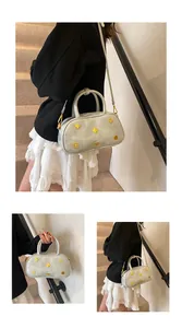 Detail view of silver Boston bag featuring gold clover metal charms and sleek finish