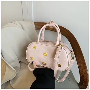 Detailed shot of pink Boston handbag with golden floral motifs and dual handle design