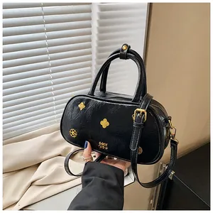 Detail of black patent leather Boston bag featuring vintage gold hardware and wrinkled texture