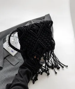 Detail of handcrafted black macrame crossbody bag with diamond patterns and long tassels