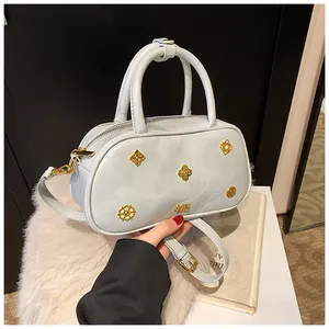 Detail of light blue Boston bag with golden floral charms and textured matte finish