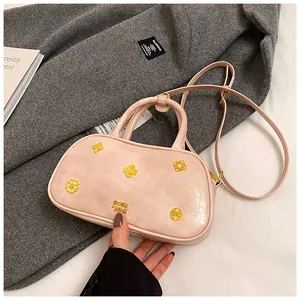 Detail view of pink Boston bag with gold relief accents and wrinkled leather texture