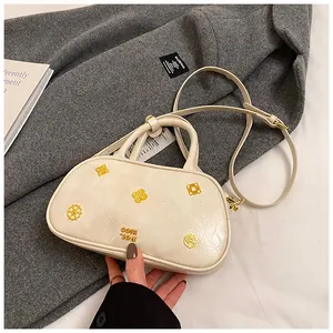 Detail of cream Boston bag with gold floral metal charms and leather texture surface